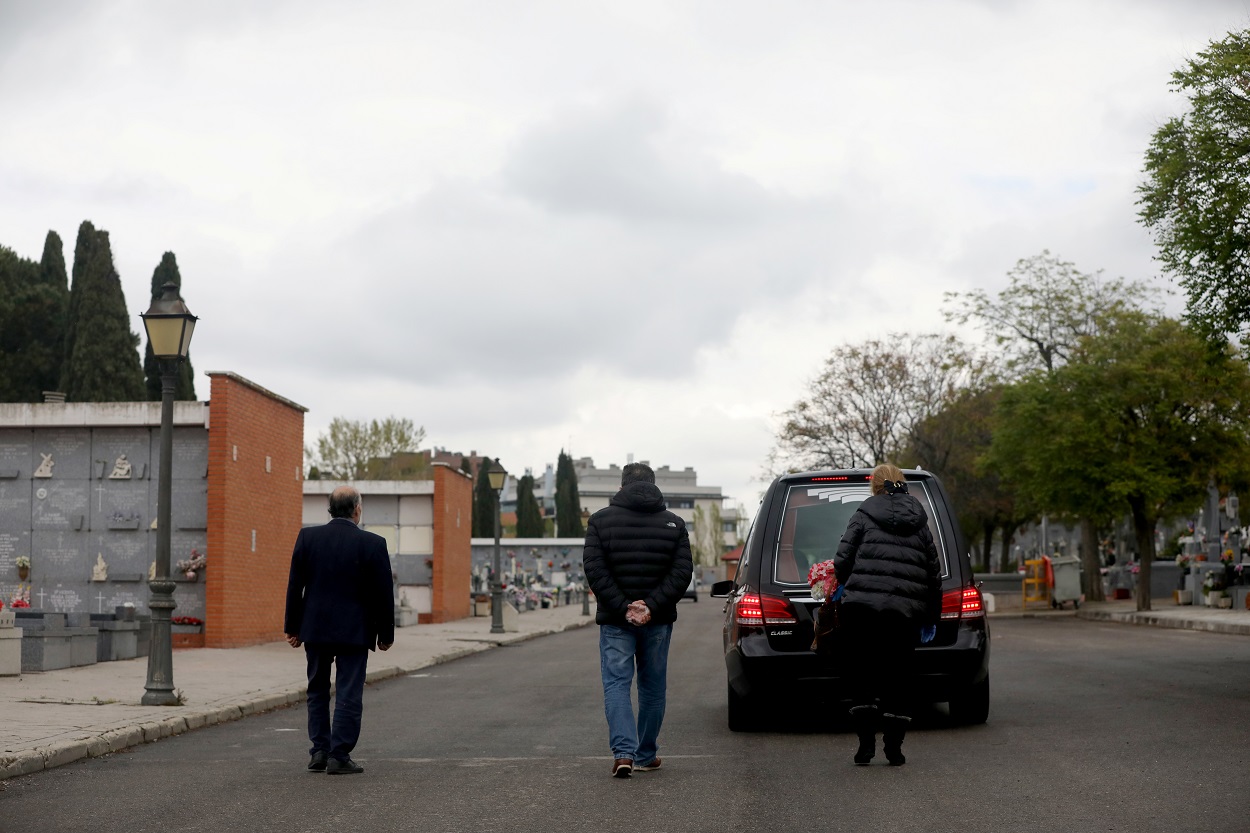 Familiares siguen el coche fúnebre con los restos de uno de los fallecidos por el coronavirus, en un cementerio de Madrid. REUTERS/Susana Vera