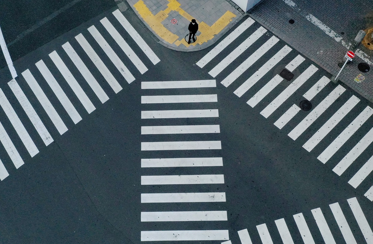 Un hombre con mascarilla parado en el conocido cruce de calles de Tokio frente a la estación de Shinjuku, prácticamente desértico por las medidas de emergencia decretadas por el gobierno japonés frente a la pandemia del coronavirus. REUTERS/Kim Kyung-Hoon