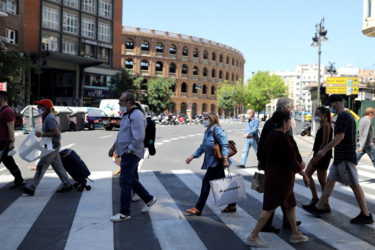 Varias personas, muchas con mascarilla, cruzan la calle cerca de la Plaza de Toros de Valencia. REUTERS/Nacho Doce