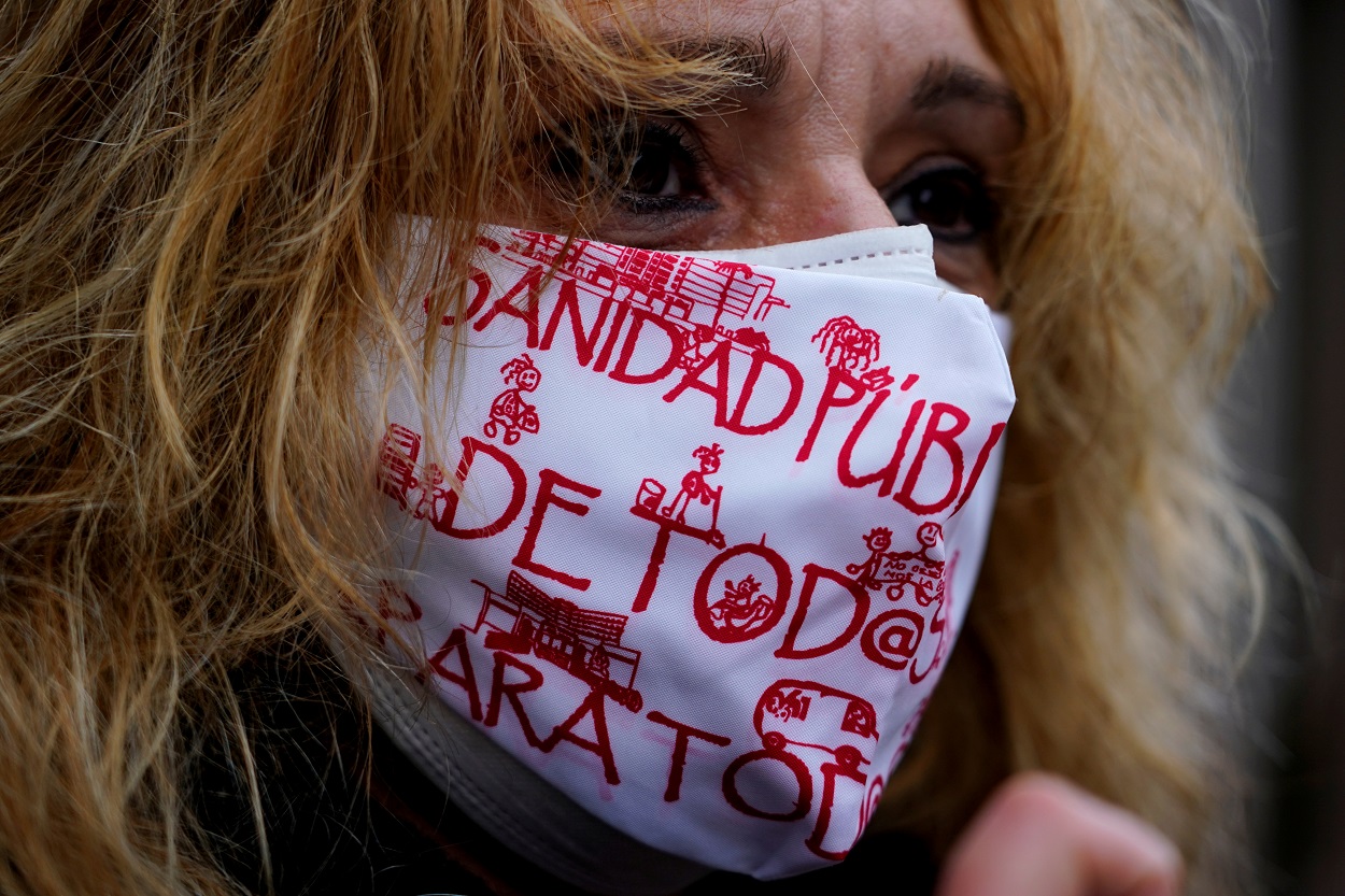 Una mujer con mascarilla, con lemas a favor de la sanidad pública, en una manifestación en Madrid. REUTERS/Juan Medina