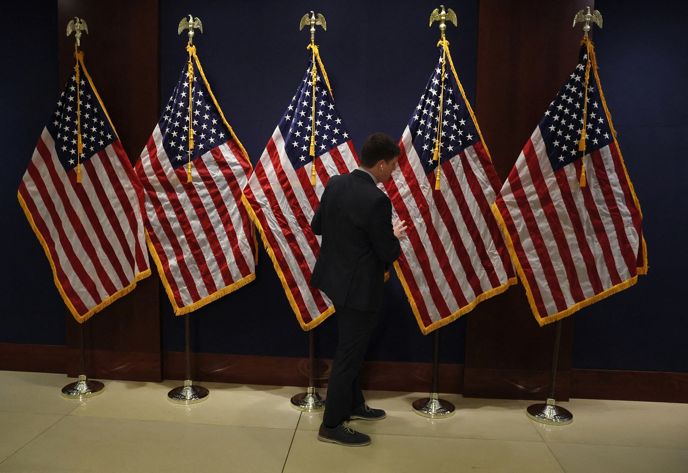 Un miembro del personal del Capitolio coloca las banderas de EEUU para la recepción de los nuevos congresistas de las recientes elecciones de 'midterm'. REUTERS/Leah Millis