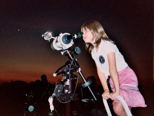 Niña mirando por un telescopio.